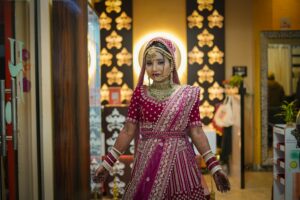 Beautiful Indian bride in traditional attire with intricate jewelry and henna, captured indoors.